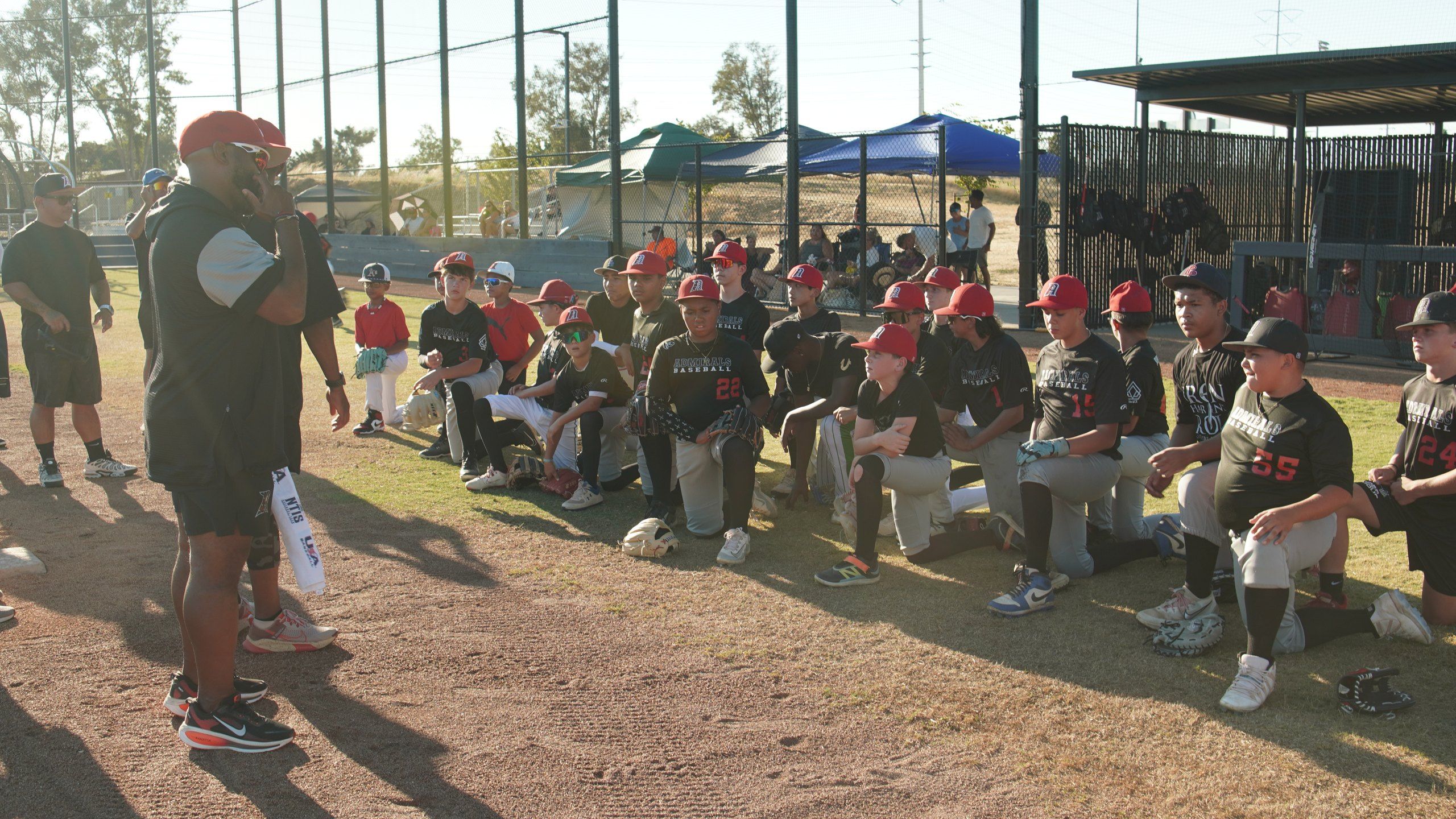 An Admirals coach talks to his players as they kneel along the first base line at a late-afternoon practice in Sacramento