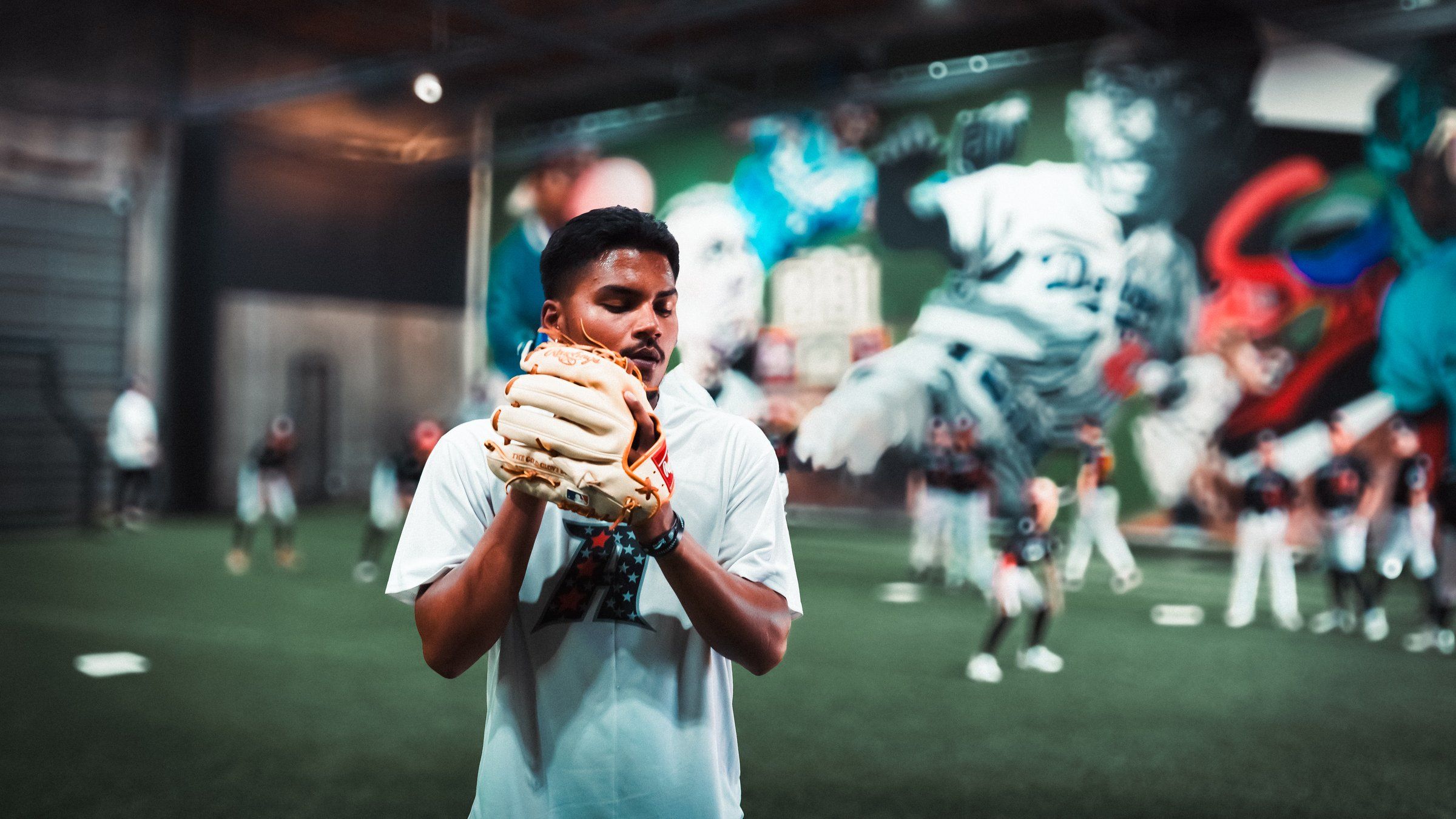 An Admirals player holds his glove at his chest during drills in front of the mural at the Sacramento facility