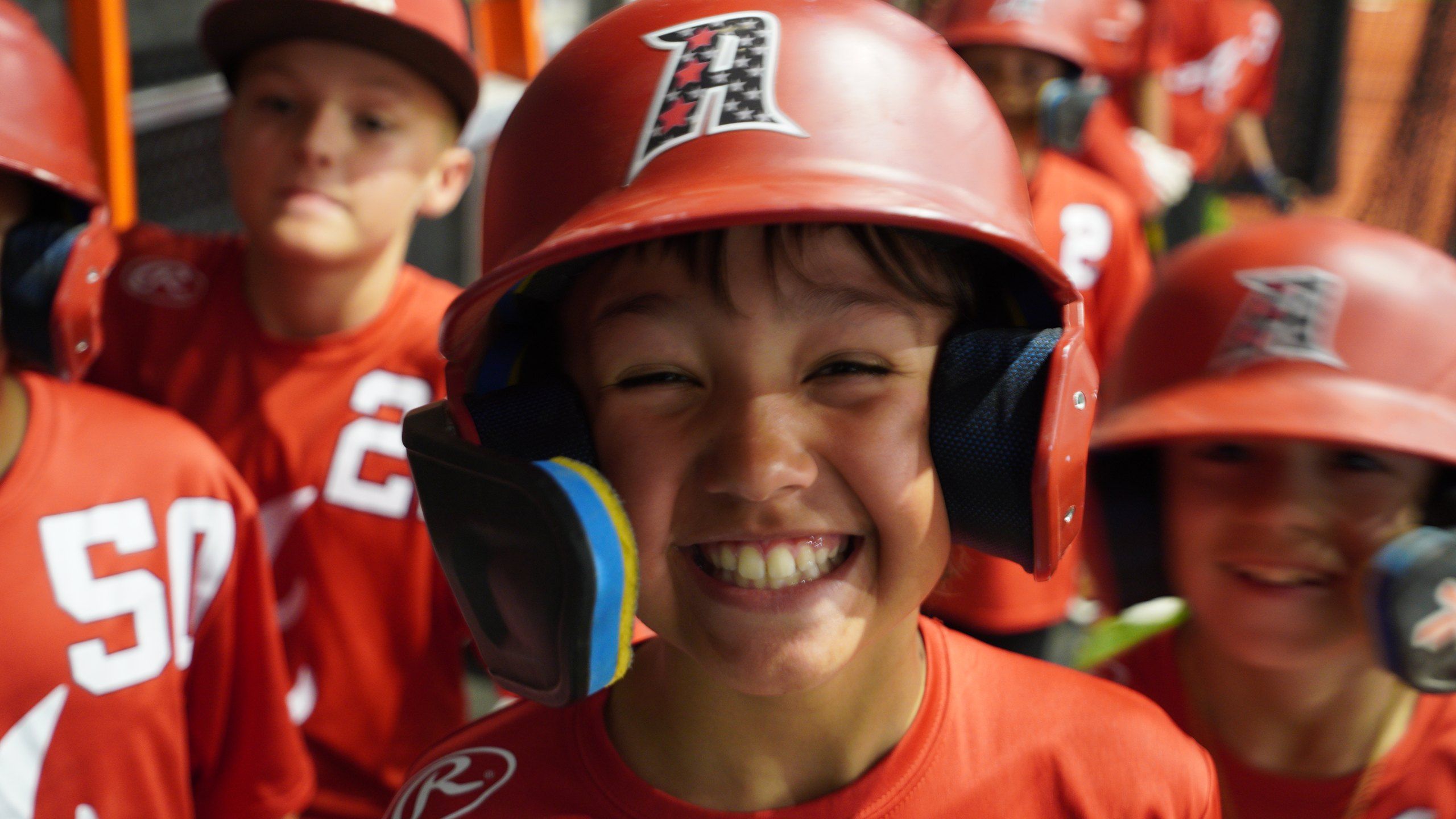 A young Admirals player in a red A helmet grins in the dugout line at The ACE in Vacaville