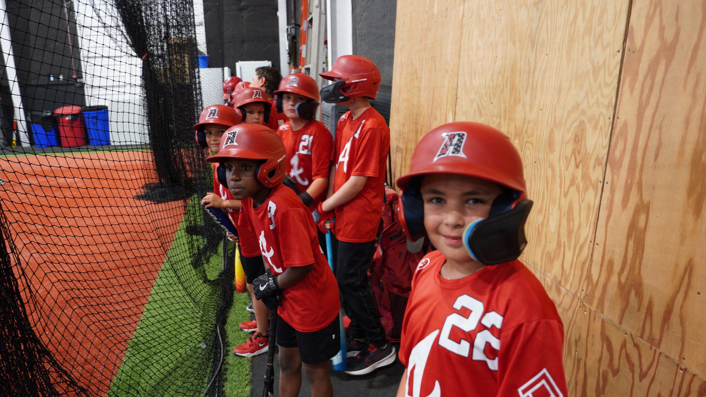 Young Admirals players in red A helmets line up by the batting cage at The ACE in Vacaville