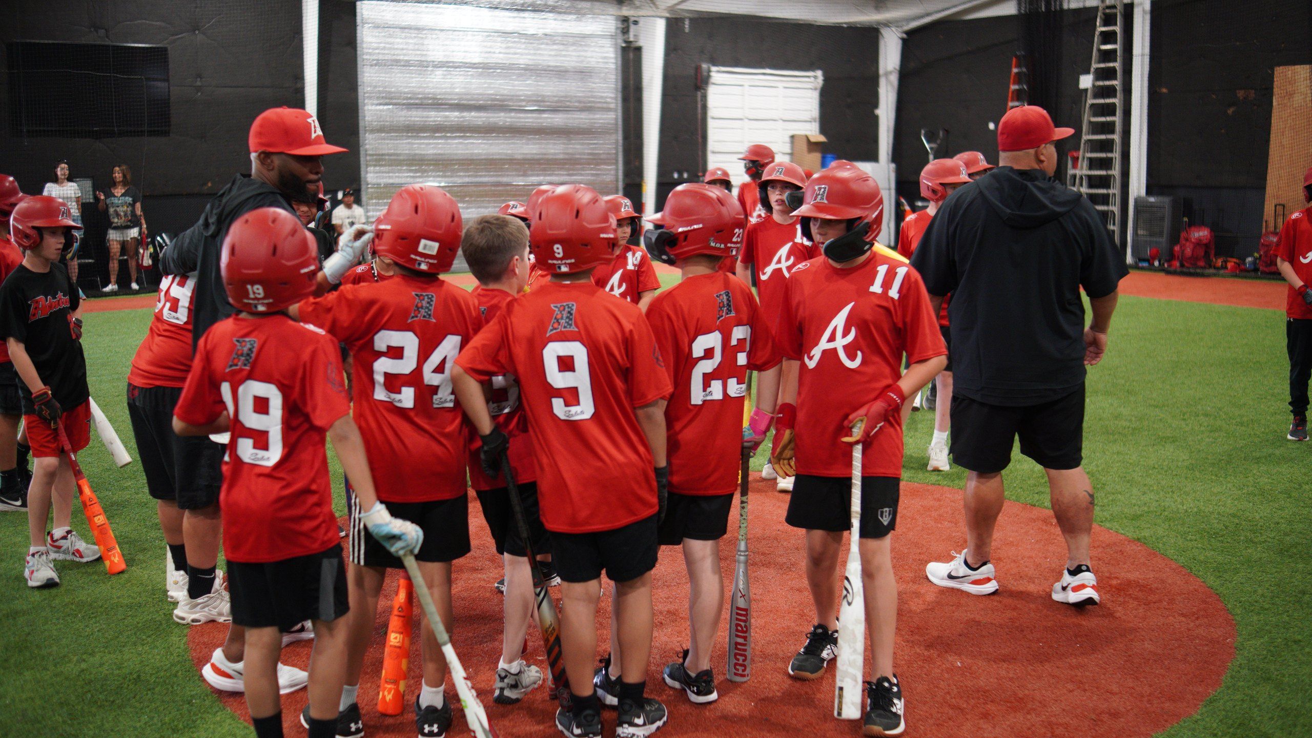 An Admirals youth team in red jerseys gathers with their coach on the turf at The ACE in Vacaville