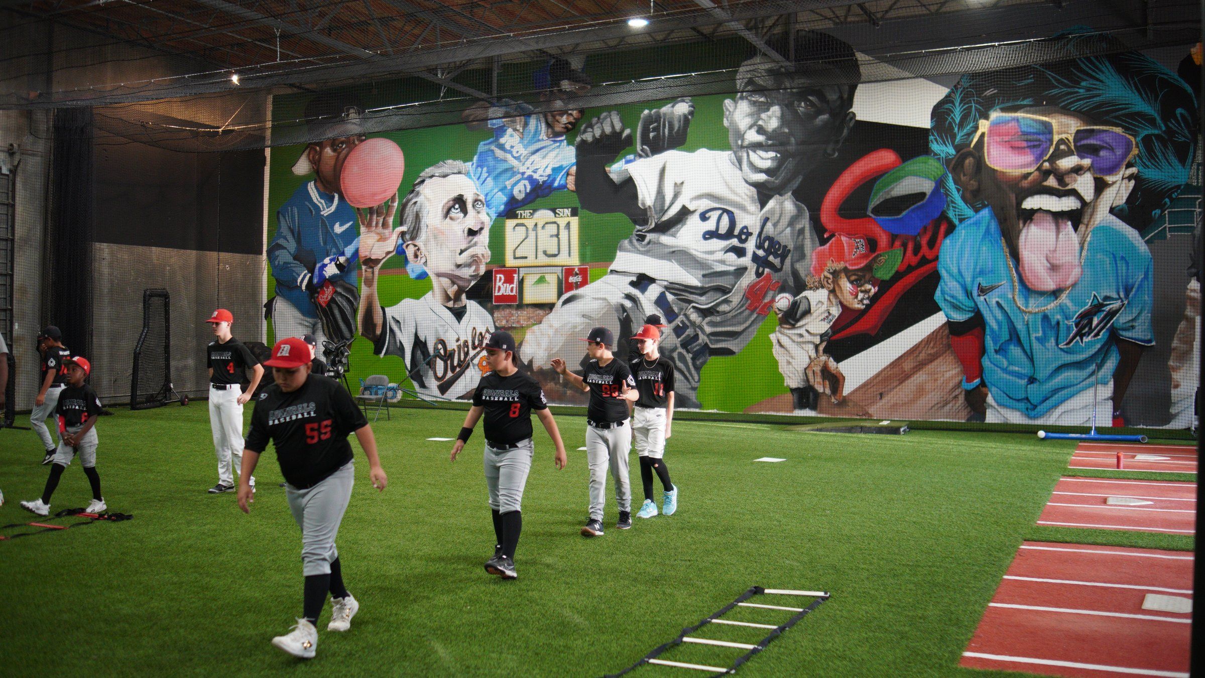 Admirals players jog across the indoor turf past a large baseball mural at the Sacramento facility