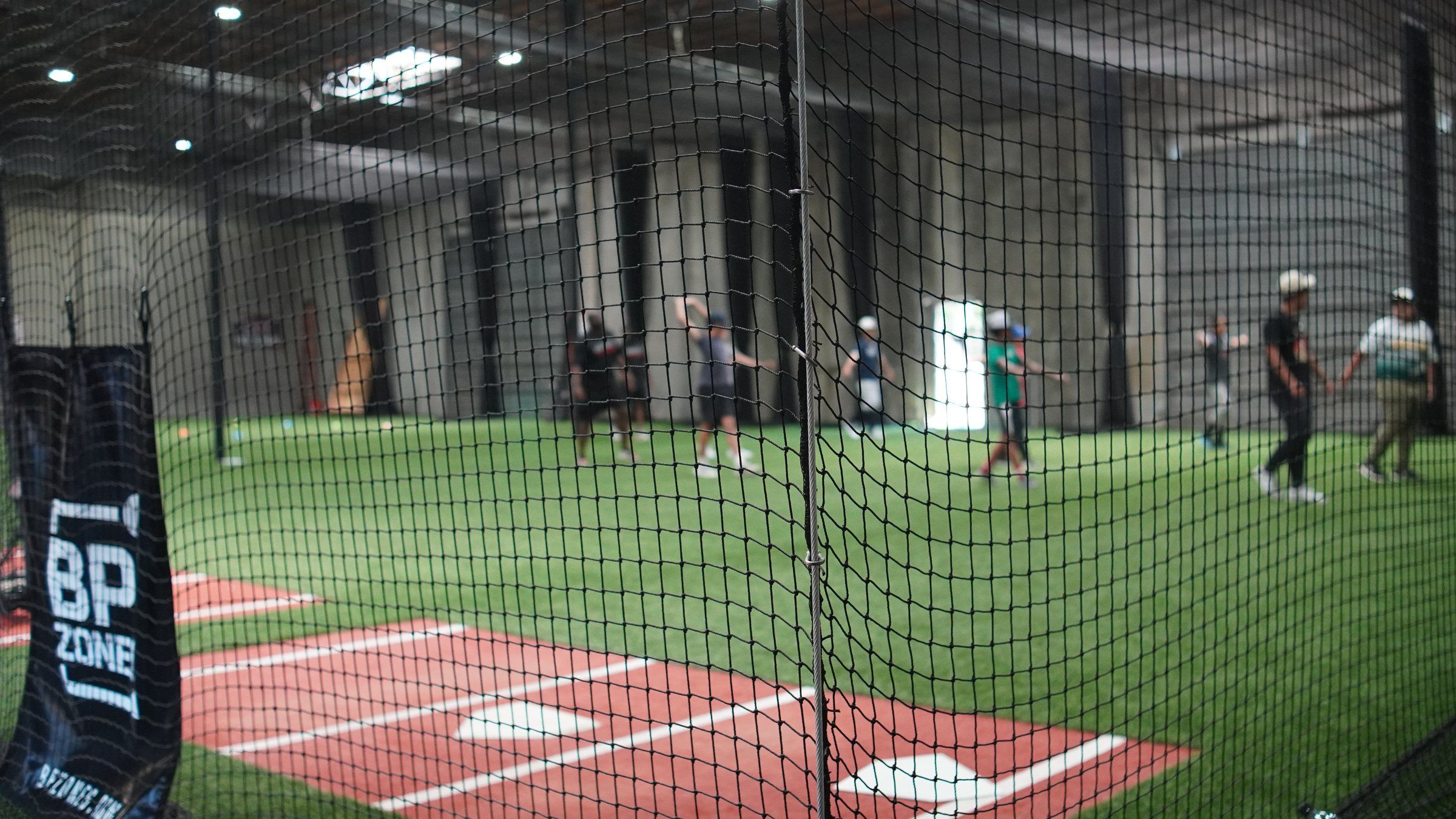 Batting cages and turf behind a BP Zone banner at the Sacramento facility