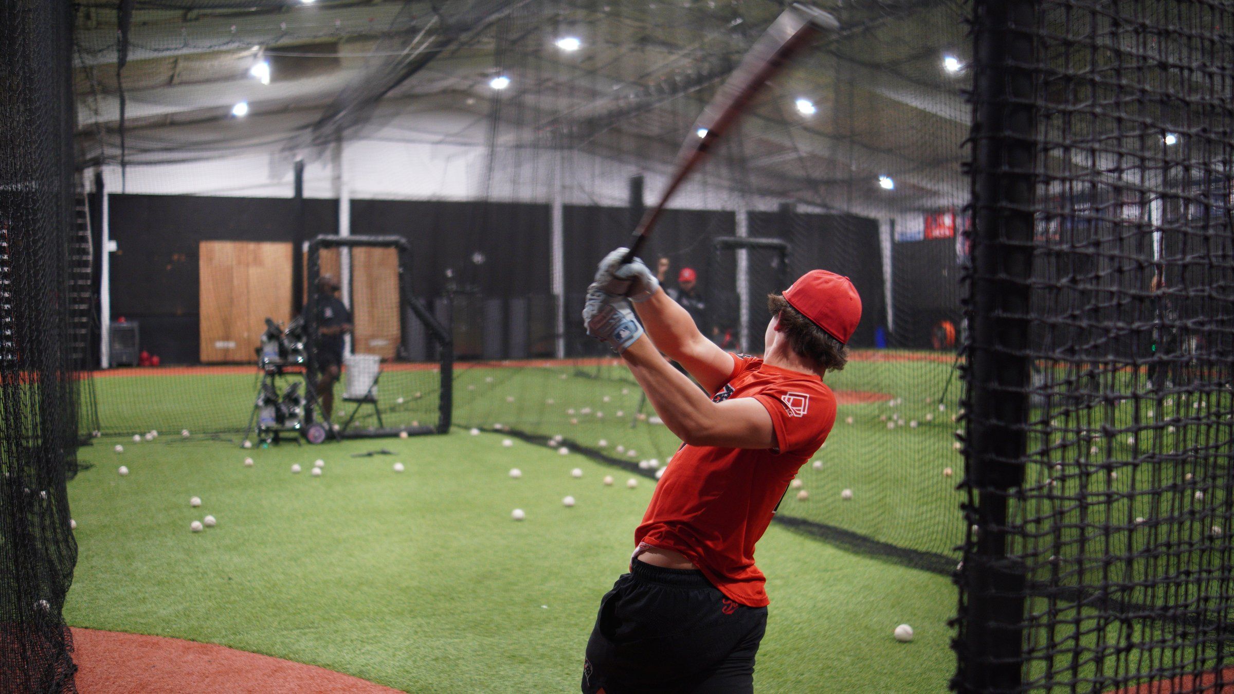 An older Admirals hitter at full extension after a swing in a batting cage at The ACE in Vacaville